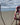borsa a tracolla colore bordeaux appoggiata su ramo sulla spiaggia, mare sullo sfondo