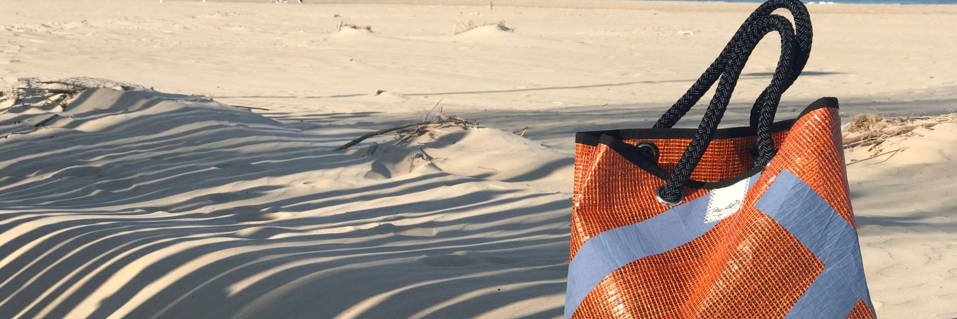 Borsa da mare arancione appoggiata sulla sabbia