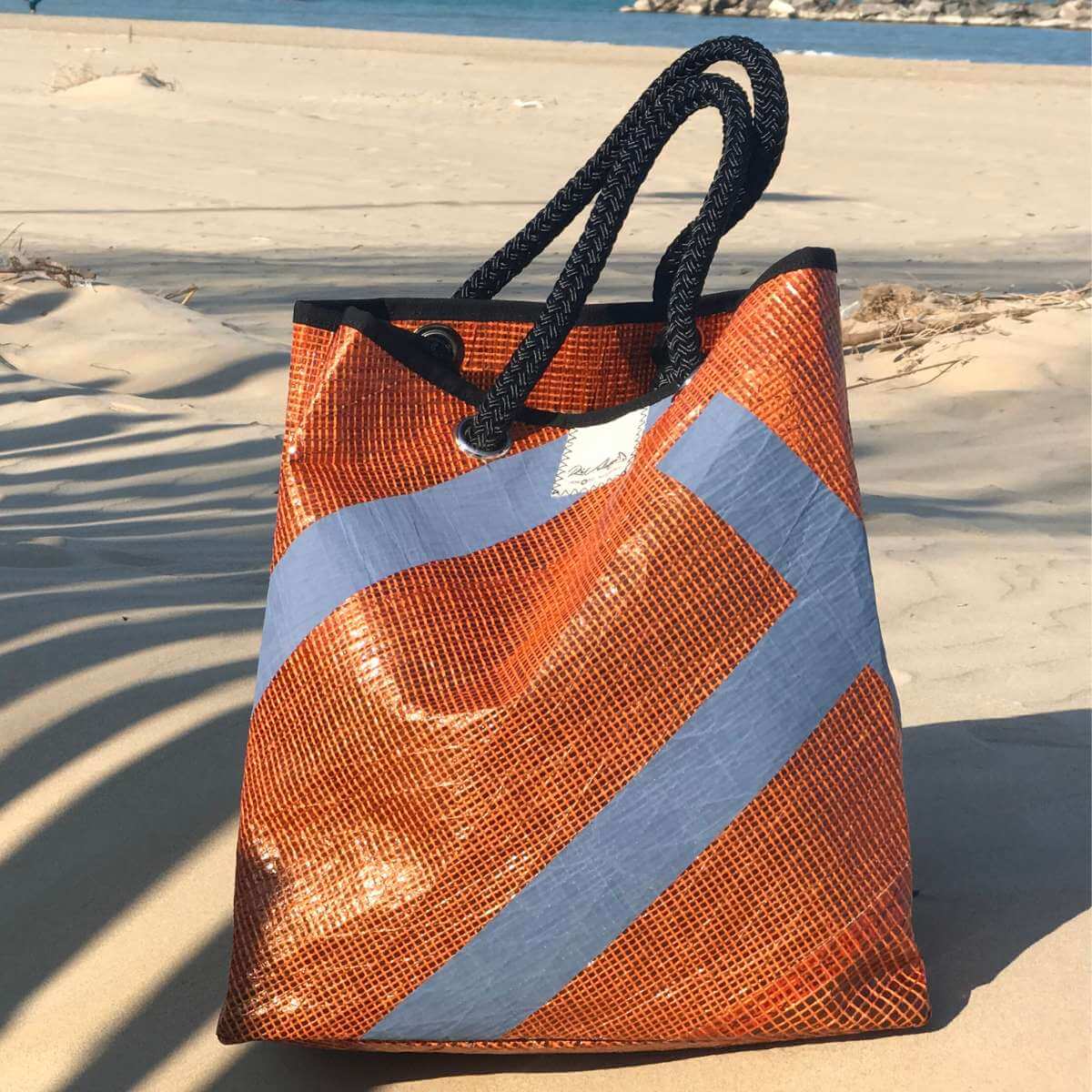 borsa da mare arancione appoggiata sulla sabbia