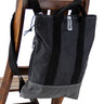zaino piccolo in tessuto tecnico colore nero appoggiato su schienale di una sedia di legno